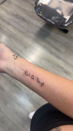 a woman with a tattoo on her arm saying eat and pray, sitting in front of a table