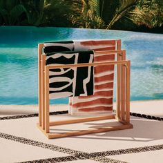 a towel rack sitting on top of a pool next to a palm tree and blue water