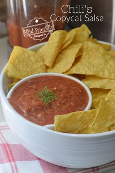 a white bowl filled with salsa and tortilla chips on top of a table