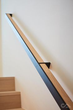 a wooden stair rail on the side of a white wall