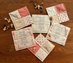 several pieces of cloth with cross stitchs on them sitting on top of a wooden table