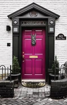 a purple door is in front of a white brick building