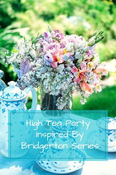 a blue and white tea party with pink flowers in a glass vase on a table