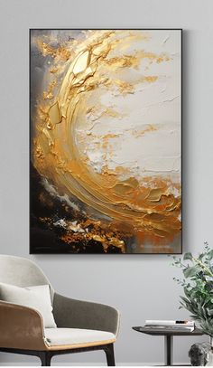 an abstract painting in gold and white on a wall above a chair with a plant