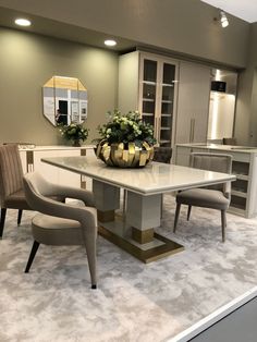 a dining room table with two chairs and a vase on the center island in front of it