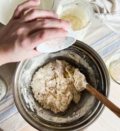 a person mixing ingredients in a bowl on top of a table