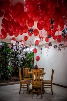 red balloons are hanging from the ceiling above a dining room table with chairs and pictures on it