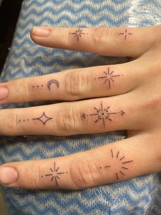 two fingers with small tattoos on them, one has an arrow and the other has stars