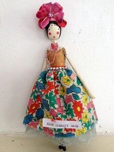 a doll is hanging on the wall with a name tag in it's hand