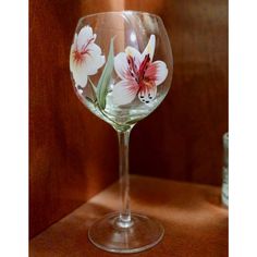 there is a wine glass with flowers painted on the bottom and inside it, sitting on a table