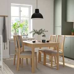 a wooden table with four chairs and a bowl on it's end in a white kitchen