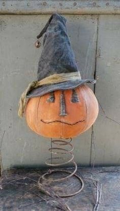 an orange pumpkin with a hat on it's head sitting on a wire stand