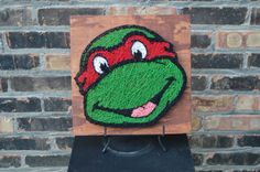 the teenaged kermie is wearing a red helmet on top of a wooden plaque