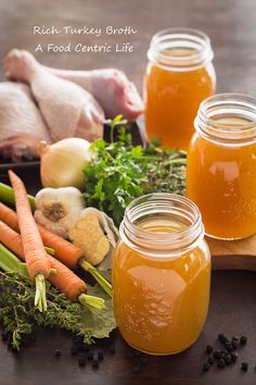 two jars filled with liquid sitting on top of a table next to vegetables and meat