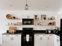 a kitchen with white cabinets and black appliances