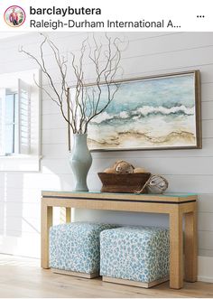 a vase filled with flowers sitting on top of a wooden table next to a painting