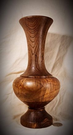 a wooden vase sitting on top of a white tablecloth covered floor next to a wall