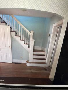 an open door in the middle of a room next to a stair case and wooden floor