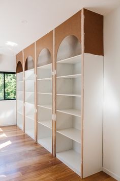 an empty room with white bookcases and wood flooring in the foreground