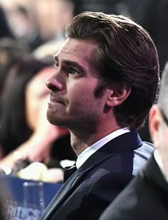 a man in a suit and tie looking off into the distance at an event with other people