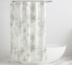 a white bath tub sitting next to a shower curtain with an abstract design on it