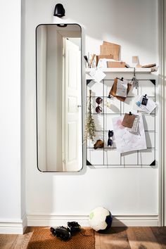 a mirror sitting on top of a white wall next to a shelf filled with items