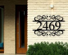 a metal address sign mounted to the side of a brick building next to a door