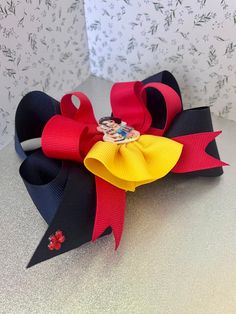 This Princess-Inspired Hair Bow is perfect for any Disney fan. Crafted with a boutique finish, this hair bow will surely bring out the royal in you. Style: large boutique bow Color: navy and red Materials: plastic button, grosgrain ribbons, resin Metal alligator clip Handmade in a clean smoke-free environment. Dimensions: Centerpiece: 2cm (w), 6cm (h) Bow: 6” (w) Alligator Clip: 3” wide Due to the handcrafted and unique nature of this product, minor differences in design, sizing, and weight will Big Bows The Hair Bow Company, Disney Faux Leather Bows, Cupcake Boutique, Disney Princess Hair Bows, Character Hair Bows, Purple Snake, Princess Hair Bows, Disney Bows, White Unicorn