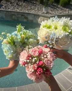 three hands holding flowers near a pool