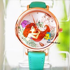 a watch with ariel the mermaid on it's face and blue strap around its wrist