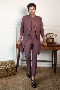 a man in a purple suit standing next to a table