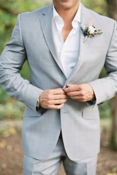 a man in a gray suit and flower boutonniere is posing for the camera