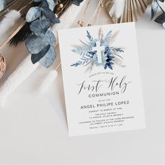 a white card with blue flowers on it next to some feathers and other things that are in the background