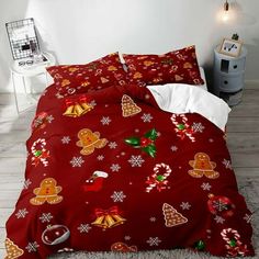 a bed covered in red and white sheets with gingerbreads on them, next to a night stand