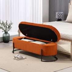 an orange ottoman sitting on top of a white carpeted floor next to a bed