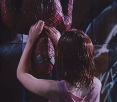 a woman standing in front of a wall with spider - man masks on it