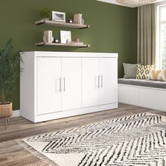 a living room with green walls and white furniture in the corner, along with a large rug on the floor