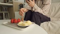 a person sitting on a couch with some fruit in front of them and a cell phone