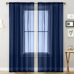 a blue curtain hanging on the side of a window next to a chair and table