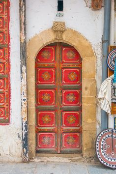 an old door is painted red and gold with intricate designs on the doors, along with other decorative items