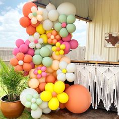 a bunch of balloons that are in the air near some grass and a potted plant