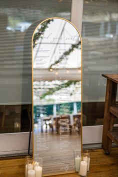 candles are placed in front of a menu on a table next to a bench and window