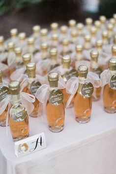 several bottles of wine are on a table with white linens and ribbons tied around them