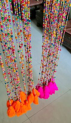 colorful beads and tassels are hanging from the ceiling in a room with tile flooring