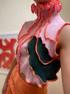 a woman wearing an orange skirt and pink top with ruffles on the back