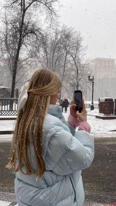 a woman taking a photo with her cell phone in the snow