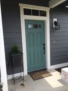 the front door of a gray house with two planters