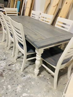 a wooden table surrounded by white chairs in a room filled with unfinished wood planks