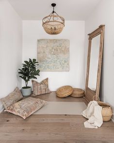 a room with a large mirror and some pillows on the floor next to a potted plant