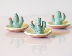 three tiny cactus figurines sitting on small plates